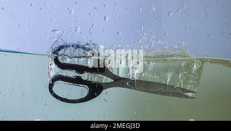 scissors fall into the water. sprays, drops and bubbles Stock Photo