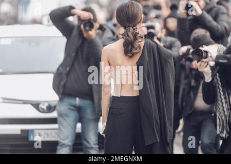 Milan, Italy - February 24, 2022: Back view of female star in top with jacket over shoulder and ponytail standing against paparazzi taking photos Stock Photo