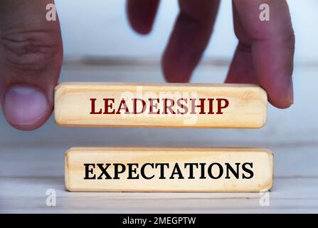 Hand holding leadership expectation text on wooden blocks. Leadership expectation concept. Stock Photo