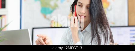 Business consultant positively talking on mobile phone working on laptop in office Stock Photo
