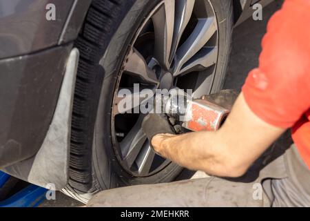 Seasonal Tires Replacement Automotive Photo Theme. Tire Sales Worker Finishing Change of Car Wheels. Closeup Photo. Stock Photo