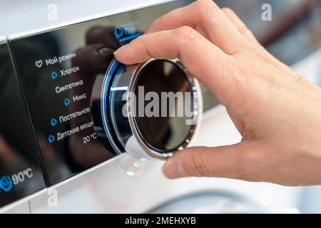 woman's hand selects the washing mode with a round selector Stock Photo