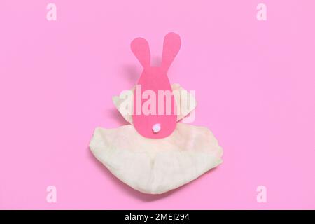 Cardboard Easter hare lies in a cabbage leaf. Pink background. Stock Photo