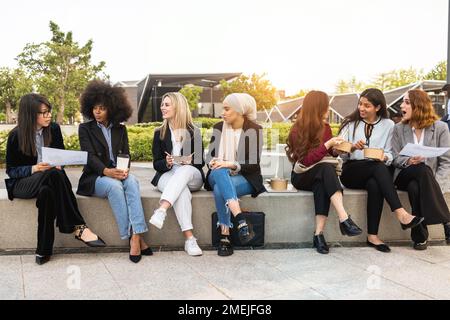 Multiethnic business women doing lunch break outdoor from office building - Soft focus on blond girl face Stock Photo