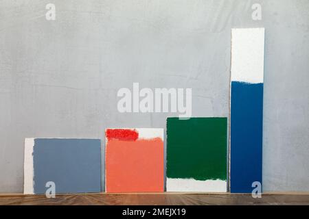 Grey red green and blue color samplers at blank gypsum plaster wall. Choosing wall paint color during house renovation Stock Photo