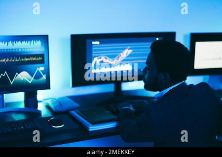 African trader working inside office at night time - Main focus on man ear Stock Photo