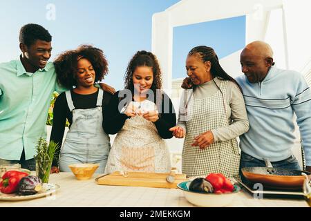 Happy african family cooking together in outdoor kitchen at home - Focus on senior woman face Stock Photo