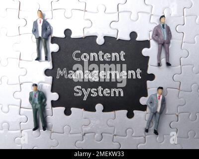Miniature people with the word CONTENT MANAGEMENT SYSTEM on black background. Stock Photo