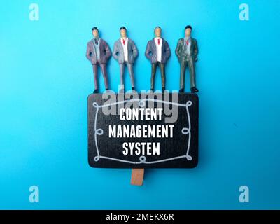 Miniature people with the word CONTENT MANAGEMENT SYSTEM on blue background. Stock Photo