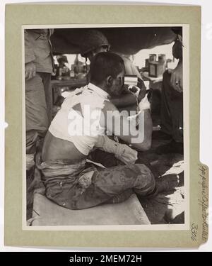 Photograph of Japanese Prisoner Drinking Coffee. Jap Prefers Yankee Coffee to Yankee Bullets. A U.S. Coast Guard combat photographer 'shoots' a captured Japanese soldier in the Marshall Islands as he awaits transfer to a prison ship. His wounds dressed, the humble Nip drains a cup of American coffee and finds a prisoner of war more comfortable than being a target for American riflemen. Stock Photo