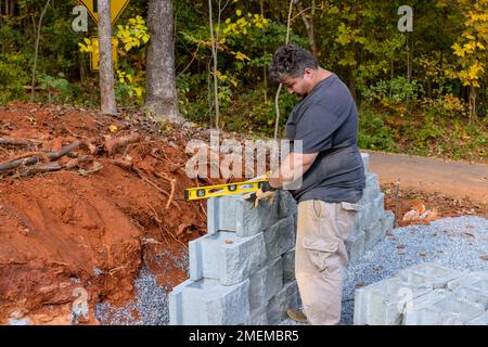 An contractor was installing concrete block after leveling walls on part new retaining wall construction project. Stock Photo