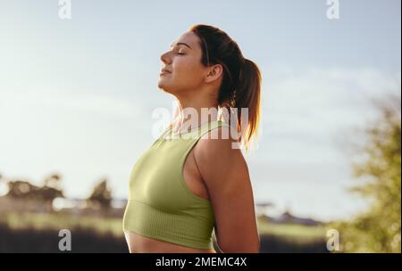 Fit woman practicing the standing cow face pose outdoors. Woman doing a warmup exercise during her morning workout. Sports woman practicing hatha yoga Stock Photo
