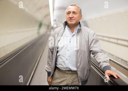Middle aged man on moving walkway Stock Photo