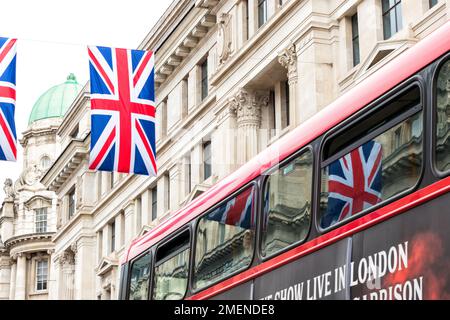 Union Jack flags reflected in the red London bus on Regent Street, London, England Stock Photo