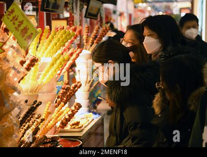 (230124) -- BEIJING, Jan. 24, 2023 (Xinhua) -- People buy Tanghulu, a traditional Chinese snack of candied fruit, in Beijing, capital of China, Jan. 23, 2023. People enjoy various kinds of cuisine in China during the Spring Festival holiday. (Xinhua/Ren Chao) Stock Photo
