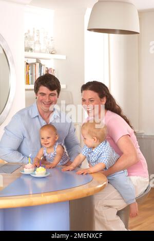 Mother and father celebrating their twin boy and girl's first birthday, front view, 1 year Stock Photo
