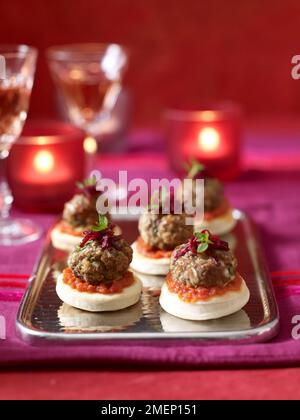Mini burger canapes served on tray on table set for dining Stock Photo