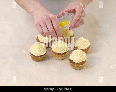 Vanilla Cream Cupcakes, decorating cupcakes with sugar sprinkles Stock Photo