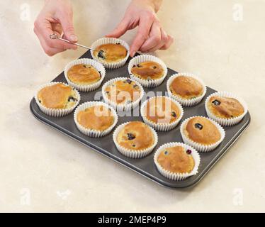 Making Lemon and Blueberry Muffins, inserting skewer Stock Photo