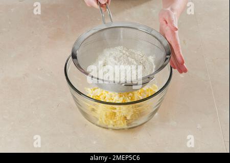Making Cinnamon Palmiers, sifting flour over grated butter Stock Photo