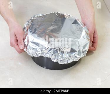 https://l450v.alamy.com/450v/2mep8kp/rich-fruit-cake-covering-tin-with-foil-before-baking-2mep8kp.jpg