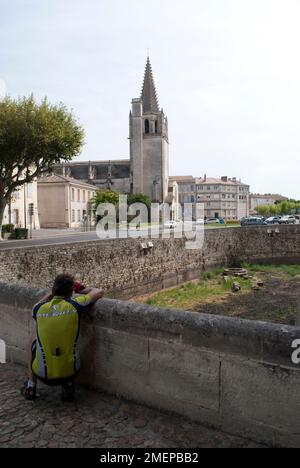 France, Bouches-du-Rhone, Tarascon, chateau, cyclist taking photo of town cathedral from chateau entrance Stock Photo