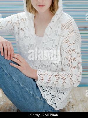 Young woman wearing white knitted lace stitch hoodie sweater Stock Photo