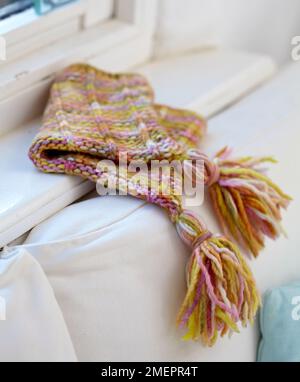 Colourful knitted tassel hat on window sill, close-up Stock Photo