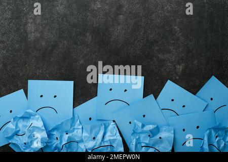 Blue crumpled sticky notes blank with drawing sad face on black background with copy space ready for your message. Blue Monday and mental health conce Stock Photo