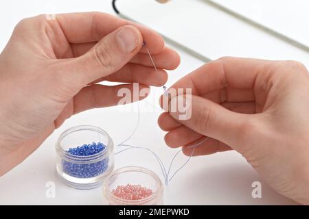 Loom weaving beads, using beading needle to thread beads on first row, close-up Stock Photo