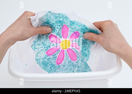Rinsing batik fabric flower in tub of warm water, close-up Stock Photo