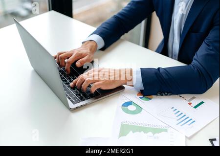 Close-up image of male hands typing on a laptop computer keyboard, searching information, browsing internet, online working. Business man chatting online, responds by email Stock Photo