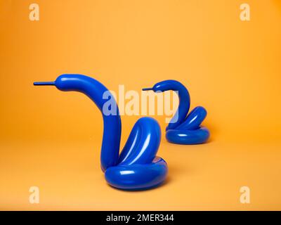 Blue balloon swans on yellow background Stock Photo