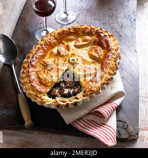 Baked crust of steak and wild mushroom pie, with part of crust missing, showing filling Stock Photo