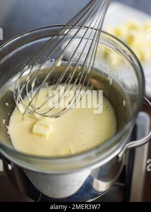 Melting in butter with yolks in heat-proof bowl set over saucepan (cooking hollandaise sauce) Stock Photo