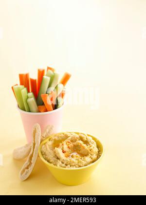 Bowl of hummus and pot of carrot and cucumber sticks with pitta bread Stock Photo