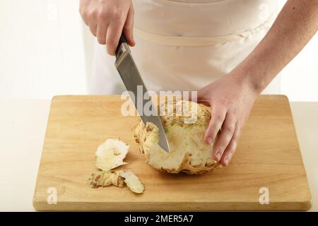 Cutting gnarled skin from celeriac Stock Photo