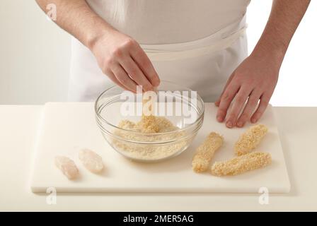 Dipping strips of cod into breadcrumbs, cod goujons Stock Photo