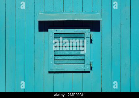 Wooden window with closed shutters on blue shed as background Stock Photo