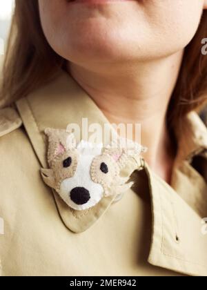 Young woman wearing felt puppy badge on collar of coat Stock Photo