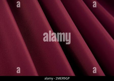 Abstract background of satin fabric or silk maroon, red with waves. View from above. The texture is purple. Valentine's Day Stock Photo