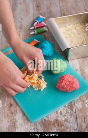 Making coconut bites, applying food colouring in kneading in Stock Photo