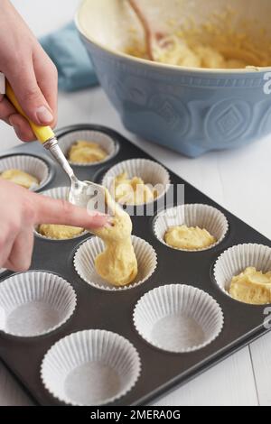 Spooning cupcake mixture into paper cases Stock Photo