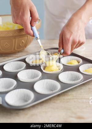 Spooning cupcake mixture into paper cases Stock Photo