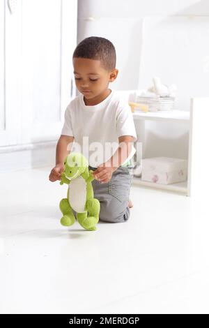Boy playing with knitted dinosaur toy, 3 years Stock Photo