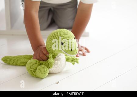Boy playing with knitted dinosaur toy, 3 years Stock Photo