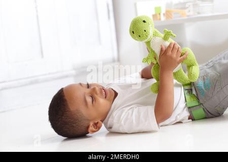 Boy playing with knitted dinosaur toy, 3 years Stock Photo
