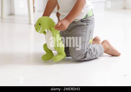 Boy playing with knitted dinosaur toy, 3 years Stock Photo