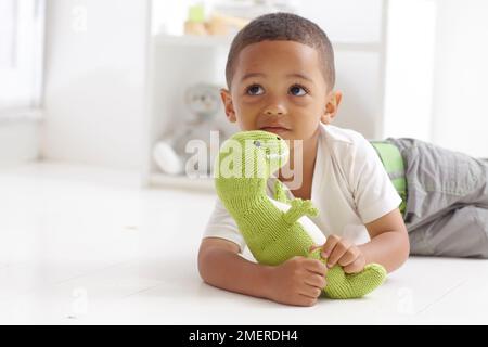 Boy playing with knitted dinosaur toy, 3 years Stock Photo
