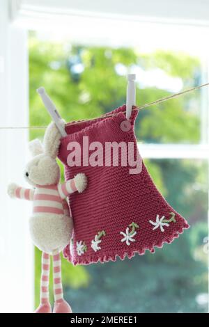 Knitted baby's skirt with daisy detail hanging from washing line Stock Photo